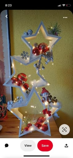 a christmas tree made out of ornaments on a wooden table with a yellow wall in the background