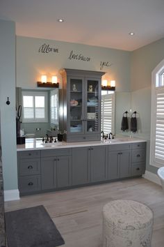 a large bathroom with two sinks and gray cabinets