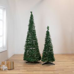 two small christmas trees sitting on top of a wooden floor