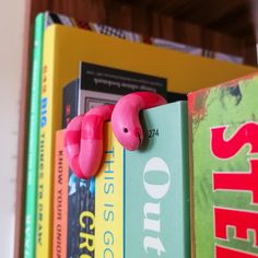 a book shelf filled with lots of books and pink toy animals on top of them