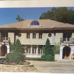 an old photo of a large house with lots of windows and bushes in front of it