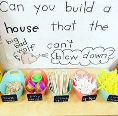 a table with bowls, cups and spoons in front of a sign that says can you build a house that the big boy can't show down?