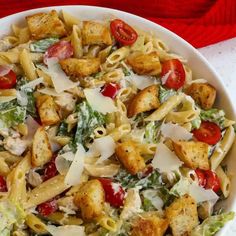 a white bowl filled with pasta salad and dressing on top of a red table cloth