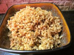 a bowl filled with brown rice on top of a black counter next to a brick wall