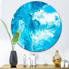 a blue circular painting on the wall in a living room with candles and vases