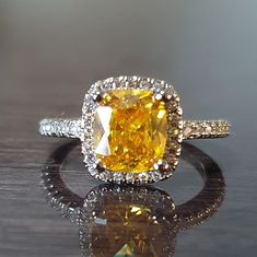 a fancy yellow diamond ring sitting on top of a table