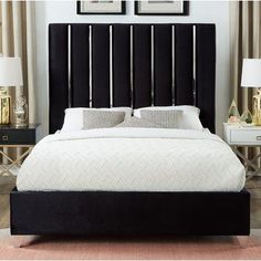 a bed with black headboard and white sheets in a room next to two nightstands