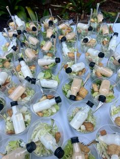 a table topped with lots of plastic containers filled with salads and dressing sauces