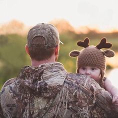 a man holding a baby wearing a deer hat