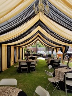 a large tent with tables and chairs set up in the grass for an outdoor function