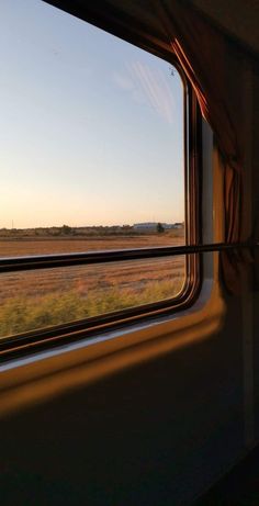 the view from inside a train window looking out at an open field