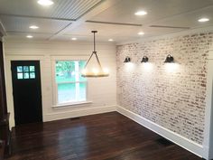 an empty room with three lights on the wall and wood floors in front of it