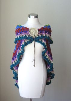 a white mannequin wearing a colorful crocheted shawl on top of it