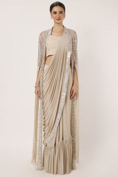 Shop a beige drape saree with statement cape sleeves. Make a fashion statement on festive occasions and weddings with designer sarees, designer suits, Indian dresses, Anarkali suits, palazzo suits, designer gowns, sharara suits, and embroidered sarees from Pure Elegance Indian fashion store in the USA. Saree Cape, Palazzo Saree, Beige Drapes, Suits Indian, Sharara Suits, Cape Designs, Drape Saree, Fashion Journals, Statement Sleeves