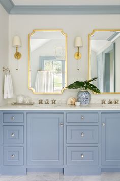 a bathroom with blue cabinets and two mirrors