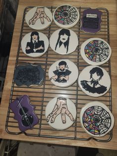 nine decorated cookies sitting on top of a wire rack with magnets attached to them