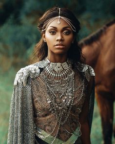 a woman in an elaborate dress standing next to a horse