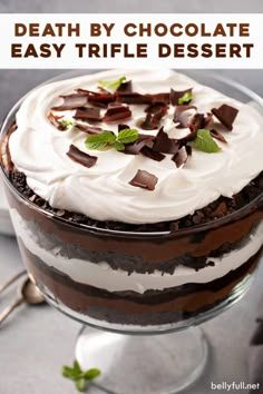 a chocolate cake with whipped cream and mint leaves on top, in a glass dish