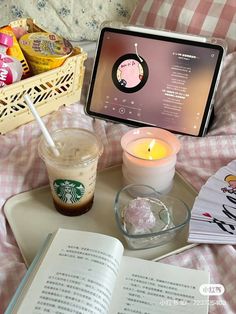 an open book on a tray next to a cup of coffee and a tablet computer