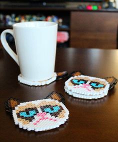 two coasters sitting on top of a table next to a cup