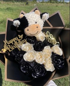 a teddy bear sitting on top of a black and white box with roses in it