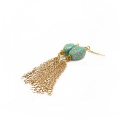 a pair of earrings with gold chains and turquoise beads