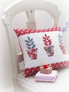 a white chair with a red and white pillow on top of it next to a stack of books