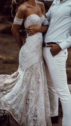 two people standing next to each other wearing white clothes and one person is holding his arm around the woman's shoulder