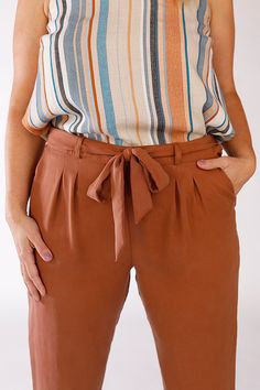 a woman wearing brown pants and a striped tank top with a tie around the waist