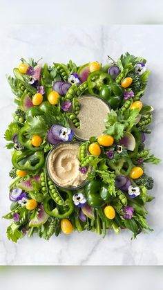 an arrangement of vegetables and dips on a marble surface