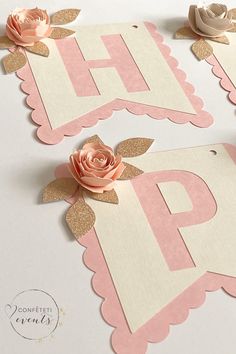 two pink and white paper cutouts with flowers on the top one is shaped like a letter