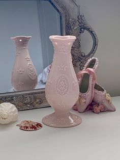 there are three vases sitting on the counter next to a mirror and shells in front of it