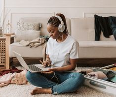 a woman is sitting on the floor with her laptop and headphones in her ears