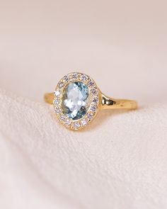 a ring with an oval shaped blue topaz surrounded by small white diamonds