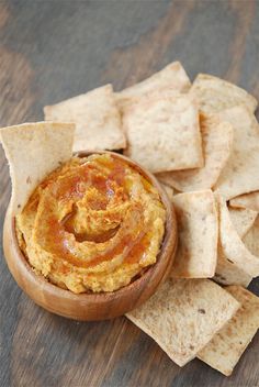 a wooden bowl filled with hummus and tortilla chips on top of a table