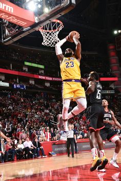 a basketball player jumping up to dunk the ball in front of two other players