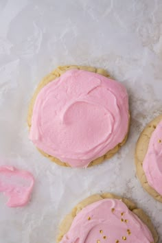 three cookies with pink frosting and gold sprinkles