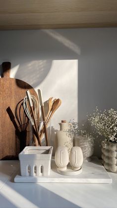 kitchen utensils are sitting on a counter next to a cutting board and vases