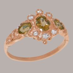 "This traditional accented trilogy ring is made completely of solid Rose Gold, and is set with three vibrant Peridots alongside six dazzling Cubic Zirconia. The ring has a delicate design with a subtle band that is low profile and comfortable to wear, while the face of the ring is is eye catching yet elegant. All the Peridots are natural, earth-mined and therefore have to be individually selected before being hand set into this ring so that they match each other in color and quality. Being hand Red Ring Box, Unique Symbols, Trilogy Ring, Delicate Design, Natural Earth, Yellow Rose, Pink Tourmaline, 18k Rose Gold, Precious Metals