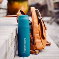 a blue insulated water bottle next to a tan purse