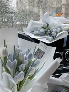 white tulips are wrapped in paper on the windshield