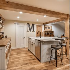 Rustic kitchen with wooden beams, white cabinets, and a central island with bar stools. Basement Beams, Basement Transformation