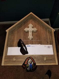 a small wooden church with a cross on the wall and other items in front of it