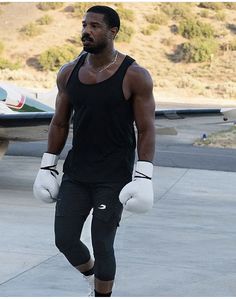 a man with boxing gloves walking towards an airplane