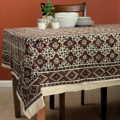 a table topped with plates and cups on top of a wooden table covered in a red and white cloth