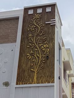 a tall building with a tree painted on it's side in gold and silver