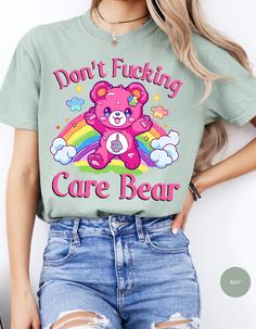 Indulge in rebellious comfort with our "I Don't Care Bear Vibes" T-shirt! This whimsical tee features a cheeky care bear boldly expressing your carefree attitude with a pair of unmistakable middle fingers and a vibrant rainbow backdrop. Crafted from soft, breathable fabric, this shirt guarantees both style and comfort. Embrace the carefree spirit and make a statement with this playful addition to your wardrobe. It's not just a shirt; it's an expression of your "don't give a care" attitude! *Unisex Sizing* Playful Slogan T-shirt With Crew Neck, Playful Slogan Crew Neck T-shirt, Trendy Crew Neck T-shirt With Bear Print, Playful Cotton Tops With Bear Print, Cute Short Sleeve T-shirt With Bear Print, Cute Bear Print Crew Neck T-shirt, Trendy Short Sleeve T-shirt With Bear Print, Graphic Tee With Bear Print For Streetwear, Casual Bear Print T-shirt For Streetwear