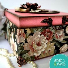 a pink and black box with flowers painted on it next to pearls, beads and necklaces