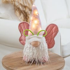 a small light - up fairy gnome sitting on top of a wooden table next to a white couch