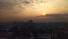 the sun is setting over a city with lots of tall buildings in the foreground